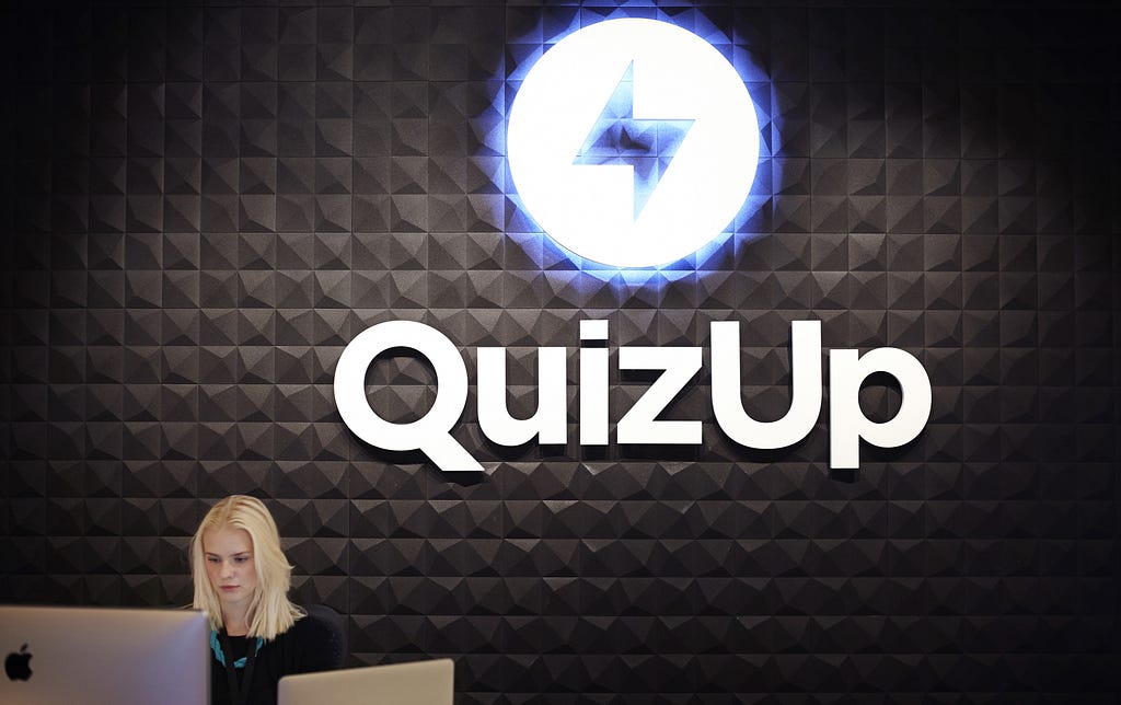 The QuizUp logo above an office reception desk.